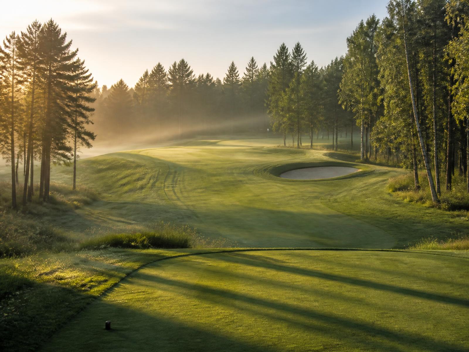 Golfhull sett fra tee med fairway, bunker og green i morgensol